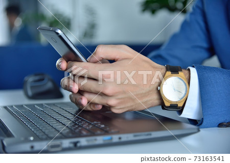 Hands with wooden watch using mobile phone. 73163541
