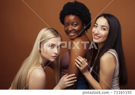 young pretty asian, caucasian, afro woman posing cheerful together on brown background, lifestyle diverse nationality people concept 73165195
