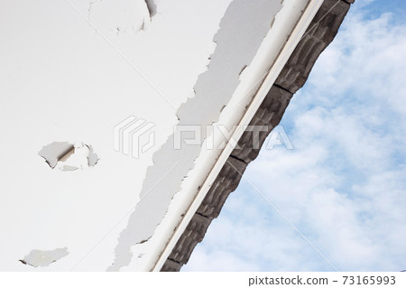 White color paint peeling off on ceiling house. Under the roof 73165993