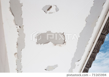 White color paint peeling off on ceiling house. Under the roof 73165994