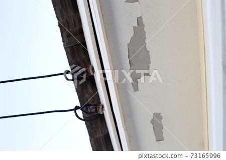 White color paint peeling off on ceiling house. Under the roof 73165996
