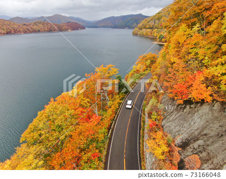 Aerial view of the autumnal road on the shores of Lake Hibara 73166048