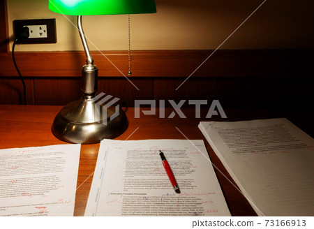 proofreading paper on wooden table under lamp light proofreading paper on wooden table under lamp light 73166913