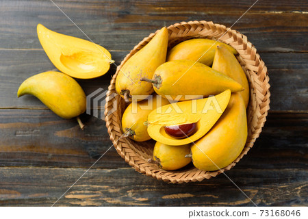 Eggfruit or canistel in a basket on wooden table, Thai fruit 73168046