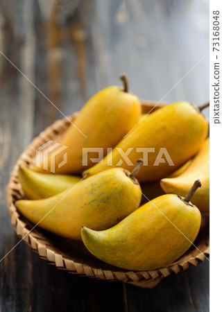 Eggfruit or canistel in a basket on wooden table, Thai fruit 73168048