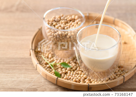 Soy milk pouring into a glass with soybeans Soy milk pouring into a glass with soybeans 73168147