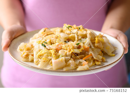 Thai food, Stir fried rice noodles with egg and chicken on dish holding by hand Thai food, Stir fried rice noodles with egg and chicken on dish holding by hand 73168152