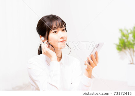 聽到在智能手機的音樂的一個少婦 73172415