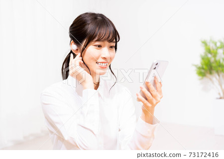 聽到在智能手機的音樂的一個少婦 73172416