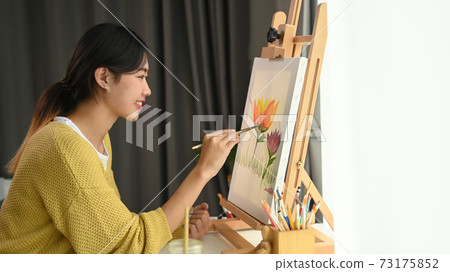 A female Artist is working on painting in bright daylight studio. A female Artist is working on painting in bright daylight studio. 73175852