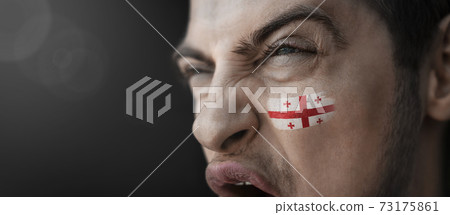 A screaming man with the image of the Georgia national flag on his face 73175861