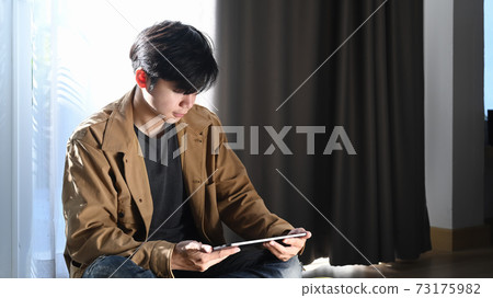 Asian man using digital tablet and sitting on... - Stock Photo ...