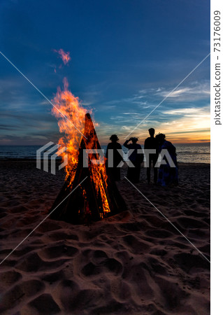 Unrecognisable people celebrating summer solstice with bonfires on beach Unrecognisable people celebrating summer solstice with bonfires on beach 73176009
