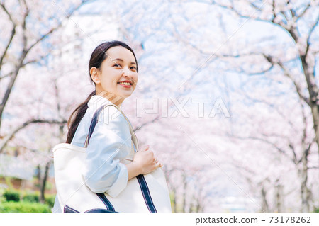 女大學生走在櫻花綠樹成蔭的校園裡 73178262