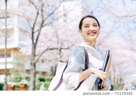 A female college student walking on a cherry blossom tree-lined campus 73178385