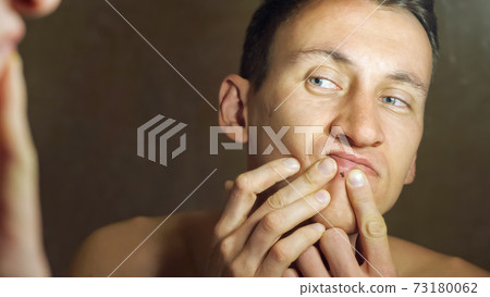 Man with grey eyes looks carefully at own mirror reflection Man with grey eyes looks carefully at own mirror reflection 73180062