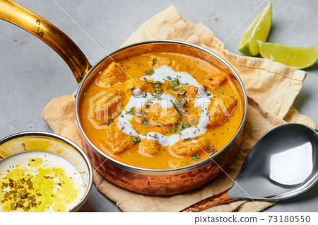 Murgh Makhani or Butter Chicken in copper bowl on gray concrete table top. Indian Cuisine dish Murgh Makhani or Butter Chicken in copper bowl on gray concrete table top. Indian Cuisine dish 73180550