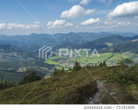 view on village Liptovska Luzna from ridge of Low Tatras mountains with mountains, hills, meadow and trees. Slovakia, summer sunny day, blue sky white clouds background 73181806