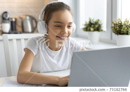 Teenager girl doing homework at home in front of a laptop monitor. 73182766