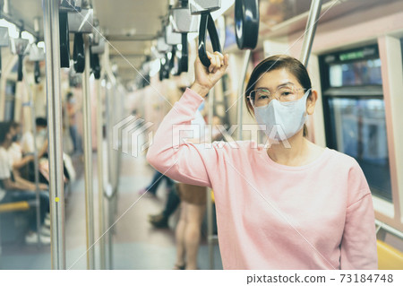 asian woman wearing protection mask standing in underground train 73184748