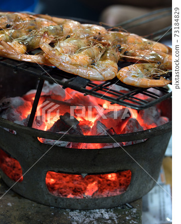 Grilled shrimps on the flaming grill. Prawns are roasted on a grill over charcoal. Grilled shrimps on the flaming grill. Prawns are roasted on a grill over charcoal. 73184829