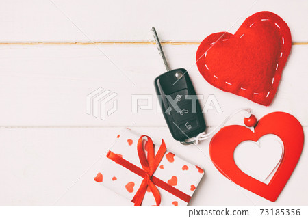 Top view of a present for Valentine's Day on wooden background. Car key, gift box and heart with copy space. Surprise concept for a holiday 73185356