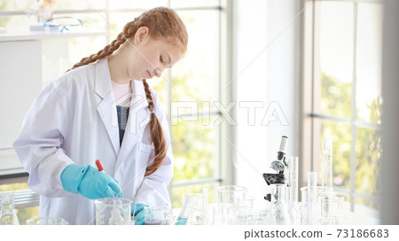 curious kid girl is experimenting science with attention face on colorful test tube 73186683