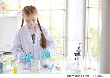 curious kid girl is experimenting science with attention face on colorful test tube 73186685