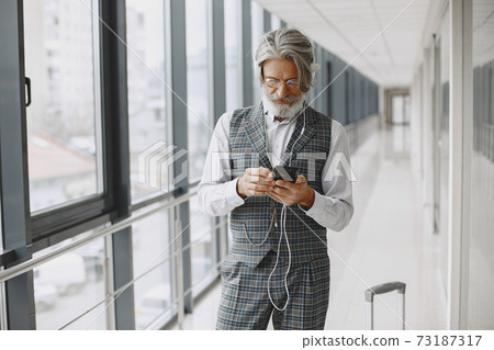 Senior businessman with travel suitcase in airport Senior businessman with travel suitcase in airport 73187317