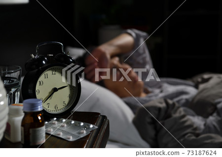 Depressed senior woman lying in bed cannot sleep from insomnia. Selective focus on alarm clock Depressed senior woman lying in bed cannot sleep from insomnia. Selective focus on alarm clock 73187624