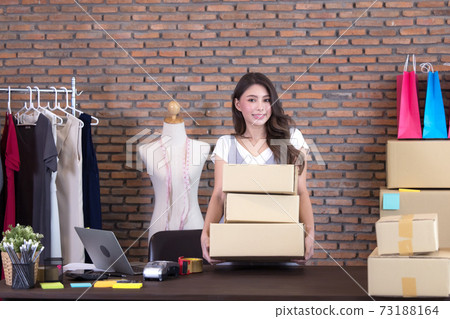 beautiful Asian woman standing among several boxes and checking parcels, working in the house office. Concept for home base business and startup ownership beautiful Asian woman standing among several boxes and checking parcels, working in the house office. Concept for home base business and startup ownership 73188164