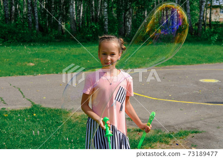 girl playing with giant soap bubbles outdoors. girl playing with giant soap bubbles outdoors. 73189477