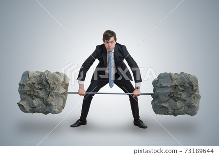 Young businessman in suit is lifting heavy weights. Young businessman in suit is lifting heavy weights. 73189644