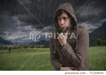 Young man feeling cold during thunderstorm. 73189648