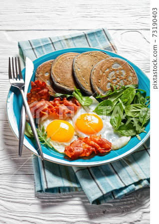buckwheat pancake with fried Eggs, bacon, greens buckwheat pancake with fried Eggs, bacon, greens 73190403