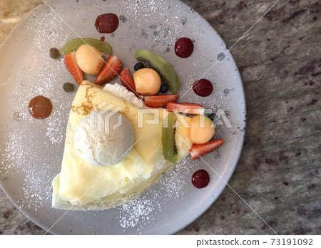 Top view of Tasty crepes with fresh strawberries, raspberries, kiwi, melon and ice cream Top view of Tasty crepes with fresh strawberries, raspberries, kiwi, melon and ice cream 73191092
