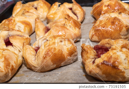 Soft focus. Rows of baked dessert envelopes with jam on a baking sheet. 73191505