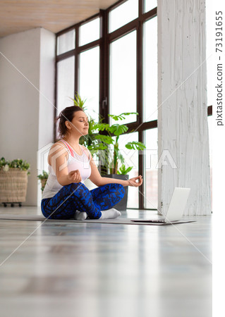 Woman meditate in front of laptop in home interior. Healthy lifestyle concept. Vertical photo. 73191655