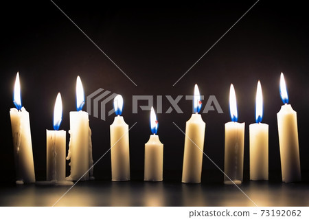 Candles glowing against dark background 73192062