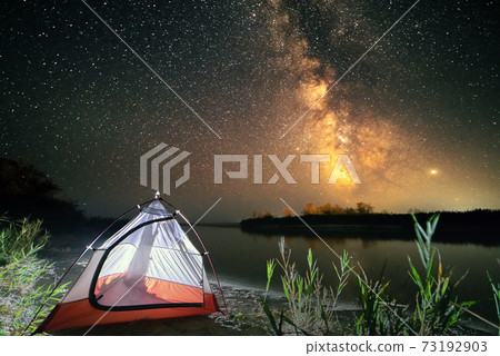 Tent on beach under fantastic starry sky 73192903