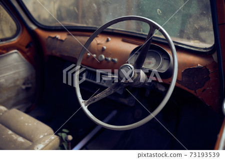 Interior of an old vintage car wreck in an old street 73193539