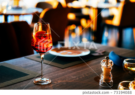 Close upof a glass with ice and orange coctail in restaurant. Close upof a glass with ice and orange coctail in restaurant. 73194088