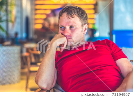 Serious blond man in casual style red t-shirt sit in modern cafe, nervous waiting someone or changes, thinking. Skin small photoshop. Human relationship, difficulties during covid or life problems Serious blond man in casual style red t-shirt sit in modern cafe, nervous waiting someone or changes, thinking. Skin small photoshop. Human relationship, difficulties during covid or life problems 73194907