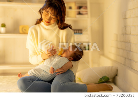 Tired woman giving milk in the middle of the night 73200355