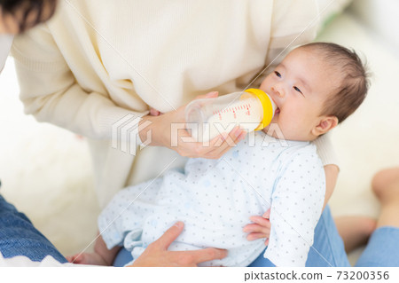 A couple giving milk to their baby 73200356