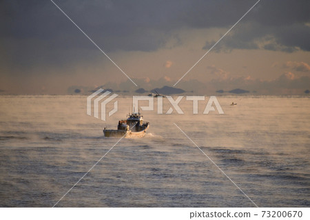 Photographing the morning scenery of a fishing boat fishing from Otoshibe fishing port in Yakumo-cho, Hokkaido in winter 73200670