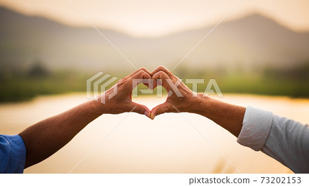 Love and Valentine day concept. A happy senior couple showing heart sign, love symbol, happy marriage, Senior healthcare and relationship. 73202153