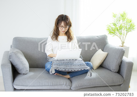 A woman looking at a computer on a telework sofa A woman looking at a computer on a telework sofa 73202783