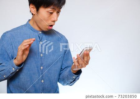 一個男人驚訝地看到一部智能手機 73203850