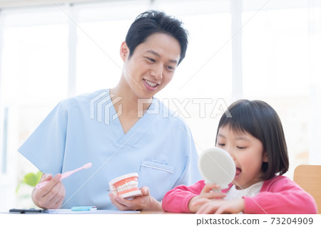 Dentist: A girl and a doctor who receive tooth brushing instruction 73204909